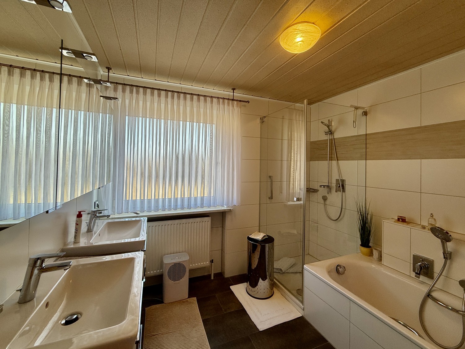 Badezimmer mit Doppelwaschbecken und Badewanne mit Dusche