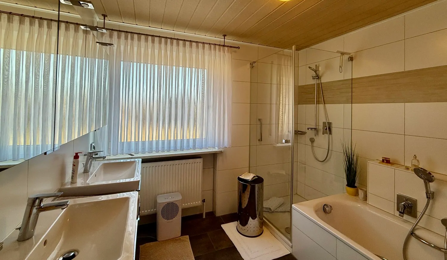 Badezimmer mit Doppelwaschbecken und Badewanne mit Dusche