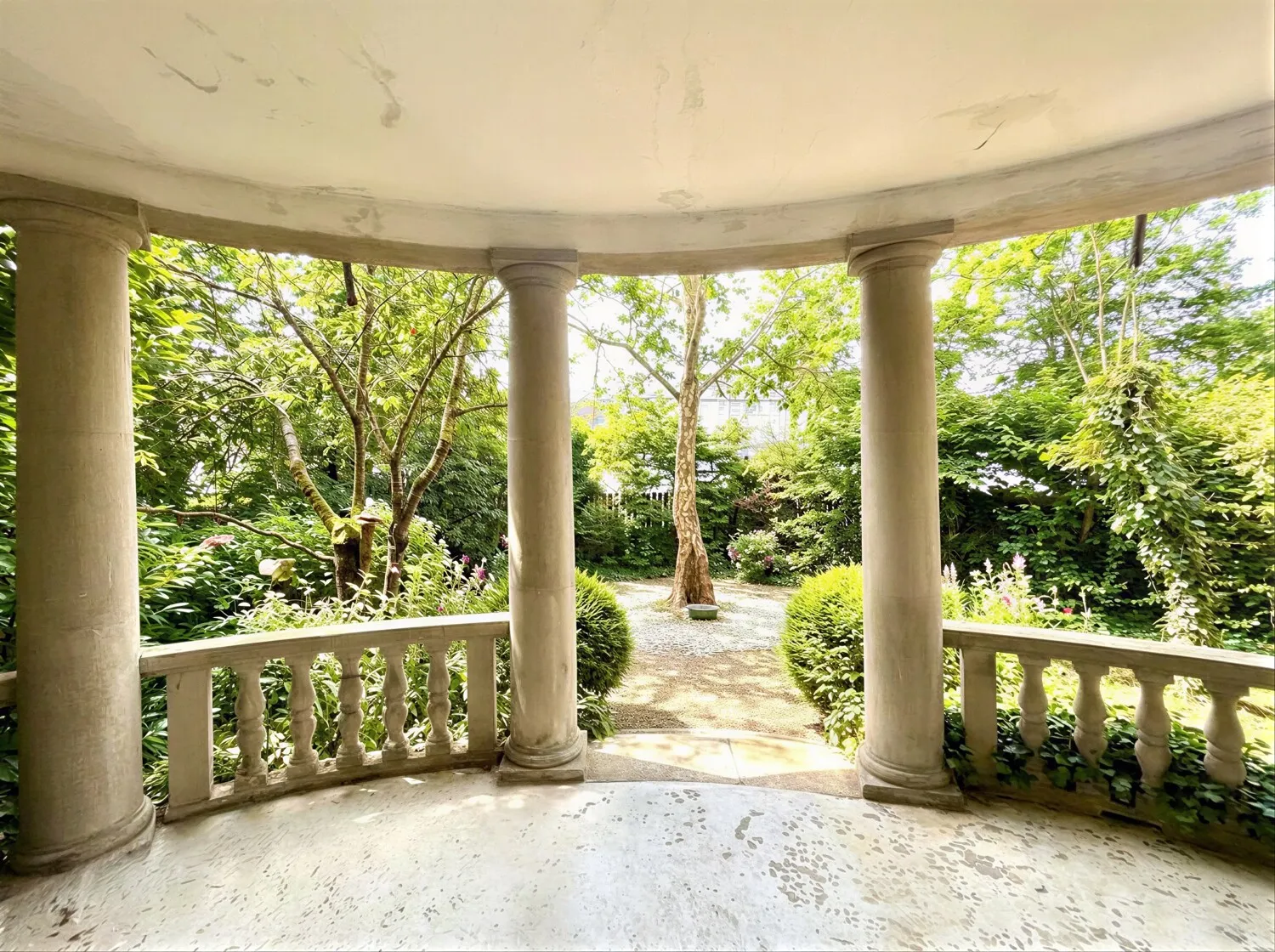 Elegante Säulenloggia mit Blick in den idyllisch angelegten Garten