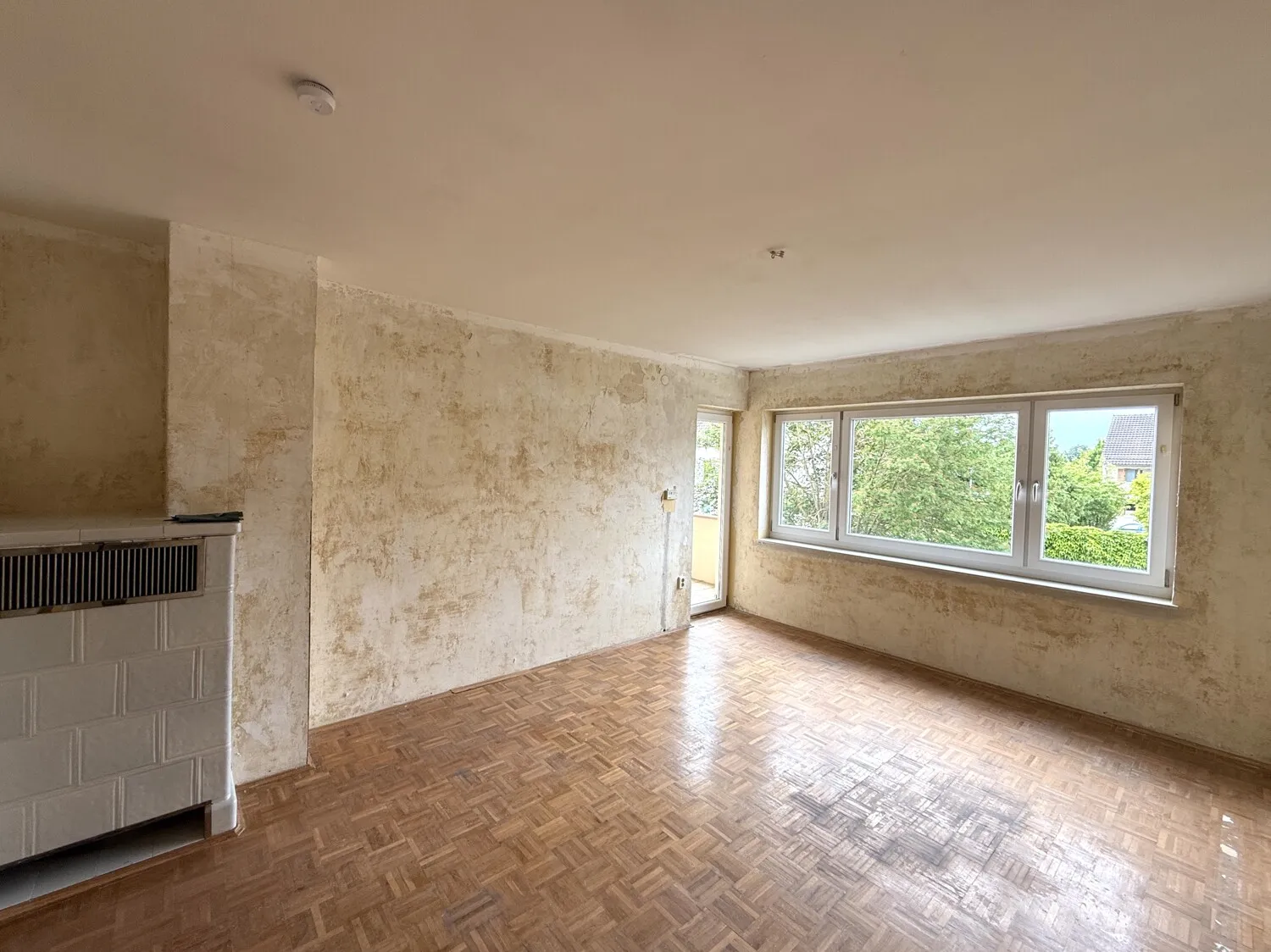Großzügiges Wohnzimmer mit breiter Fensterfront und Zugang zur Loggia