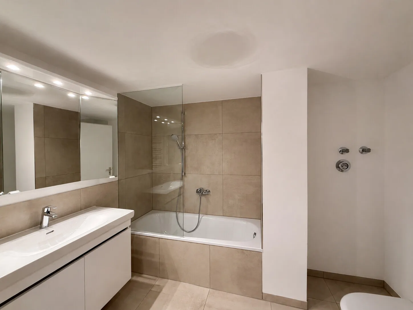Modernisiertes Badezimmer mit Badewanne und Glasabtrennung