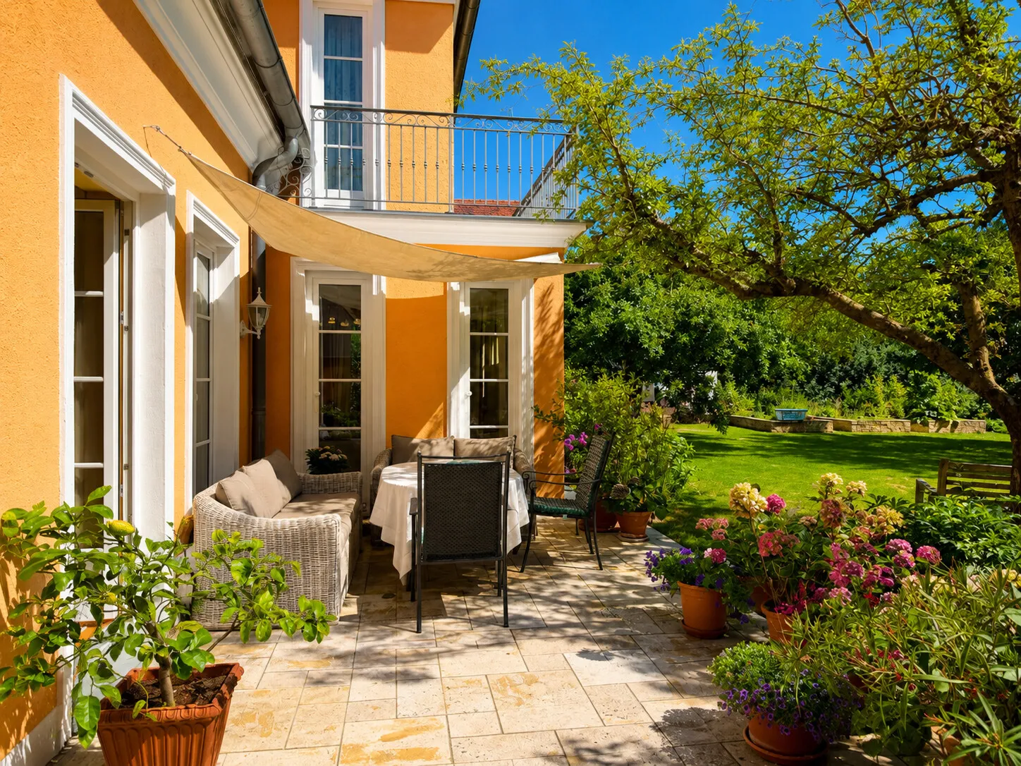 Sonnige Travertinterrasse mit Blick in den parkähnlichen Garten