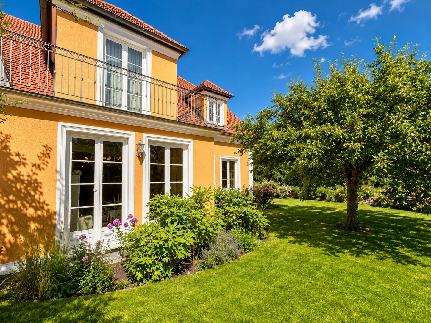 Harmonische Gartenfassade mit bodentiefen Sprossenfenstern