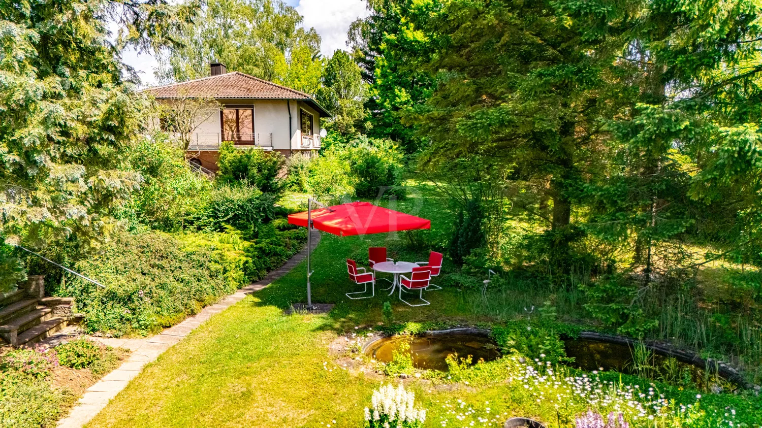 Blick auf die Villa vom Gartenteich mit Sitzplatz