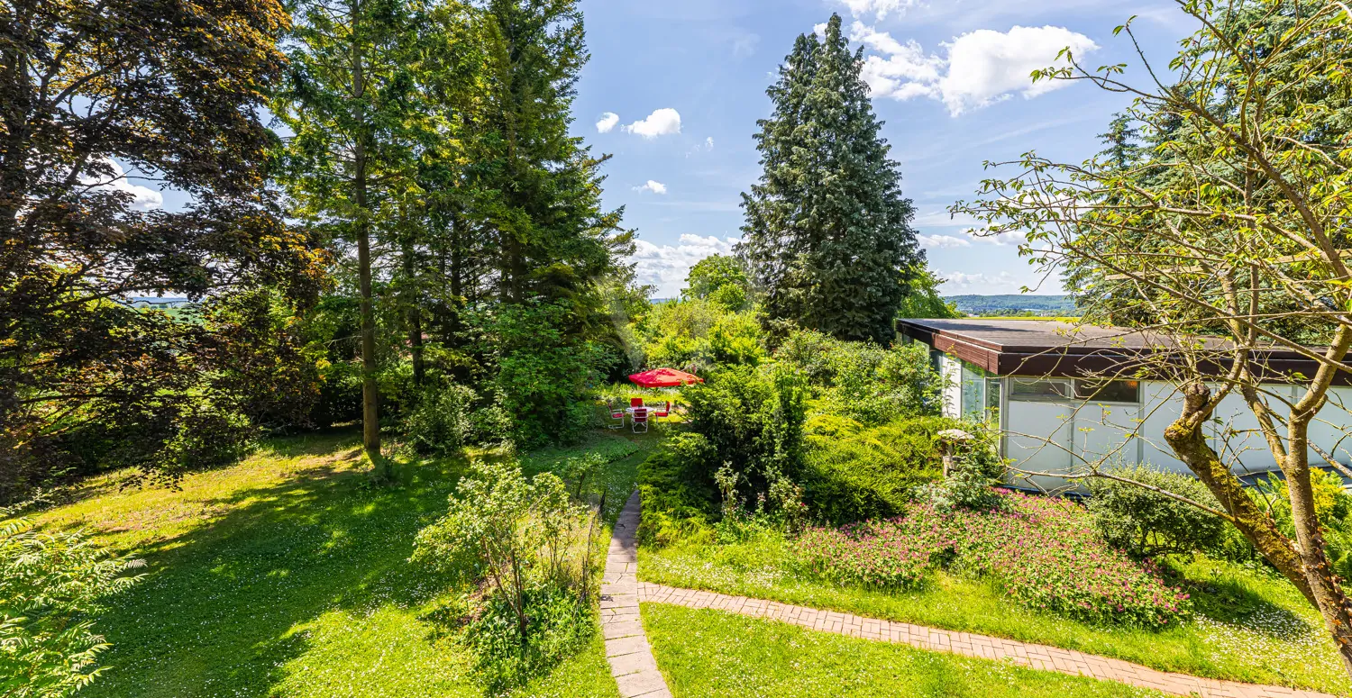 Blick von der Terrasse der Villa auf Garten und Poolhaus
