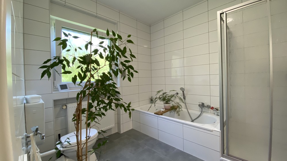 Helles neuwertiges Badezimmer mit Wanne und Dusche