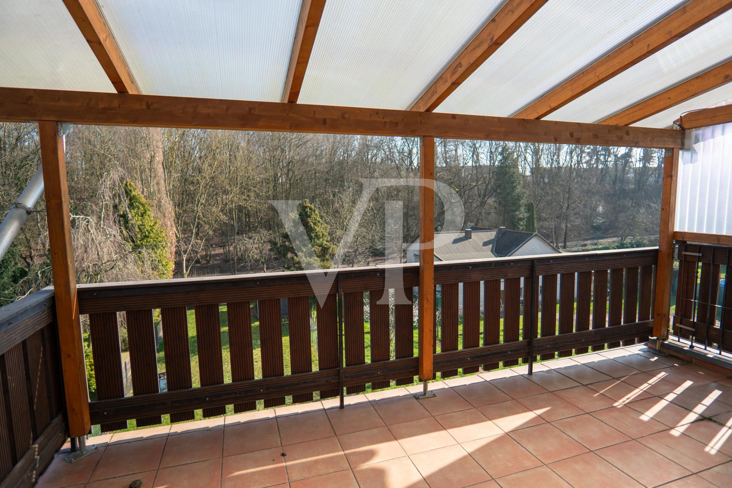 Überdachter Balkon mit Blick auf Garten und Wald