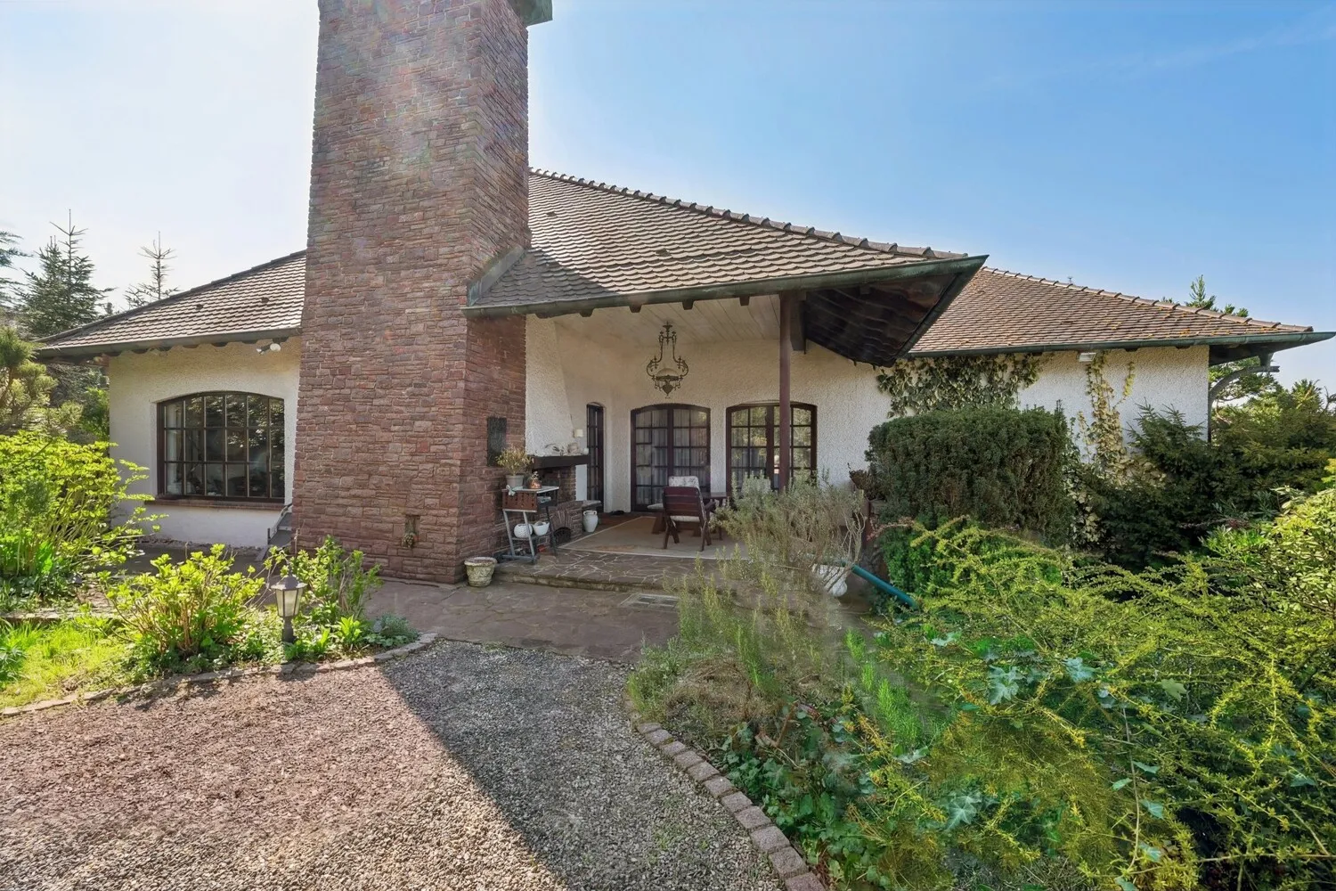Exklusive Gartenansicht mit überdachter Terrasse und Kamin
