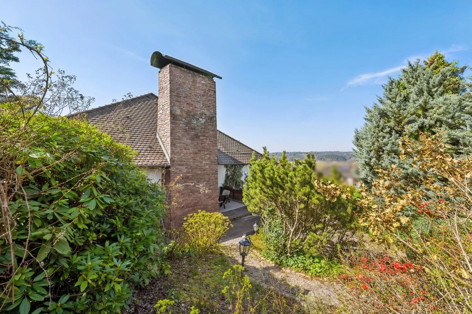 Exklusive Gartenansicht mit überdachter Terrasse und Kamin