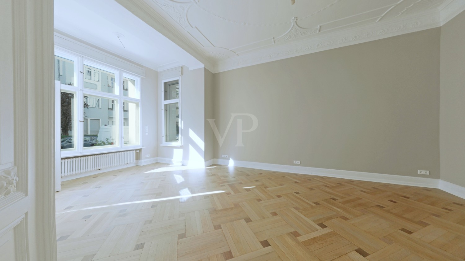 Blick ins Wohnzimmer mit Balkon und Tafelparkett