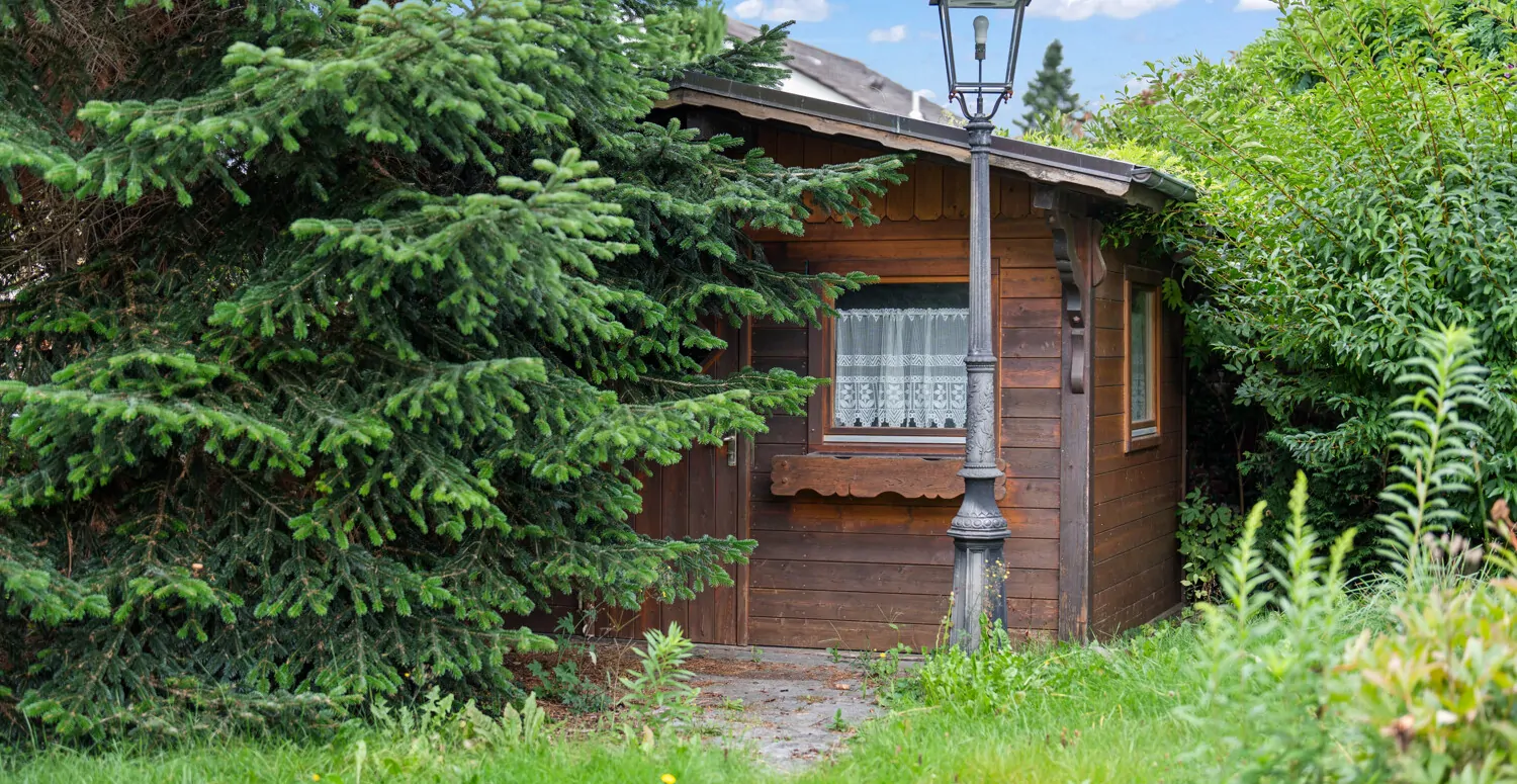 Blick auf das Gartenhaus mit altem Baumbestand