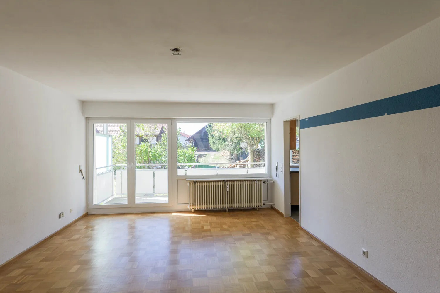 Wohnzimmer mit Zugang zum Balkon und Küche