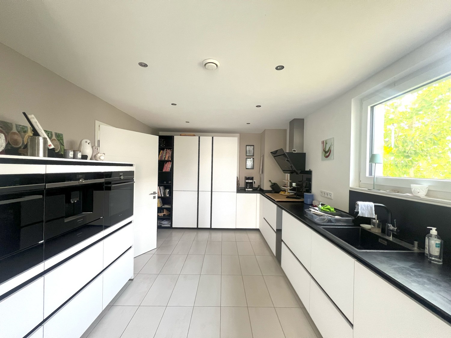 Moderne Einbauküche mit separater Speisekammer und Zugang zur überdachten Terrasse