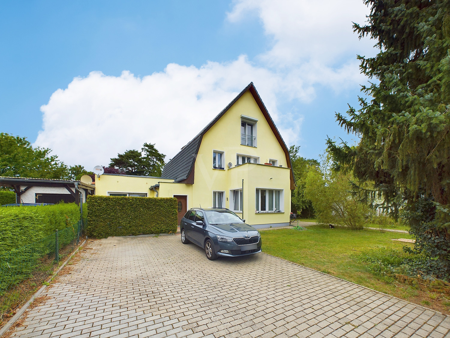 Hausansicht von vorne mit Blick in den Vorgarten und auf die Einfahrt