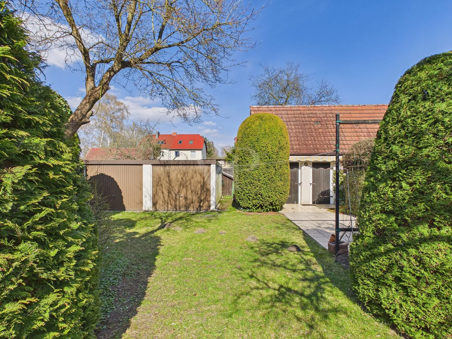 Blick in den Garten und auf die Garagen sowie das Nebengelass