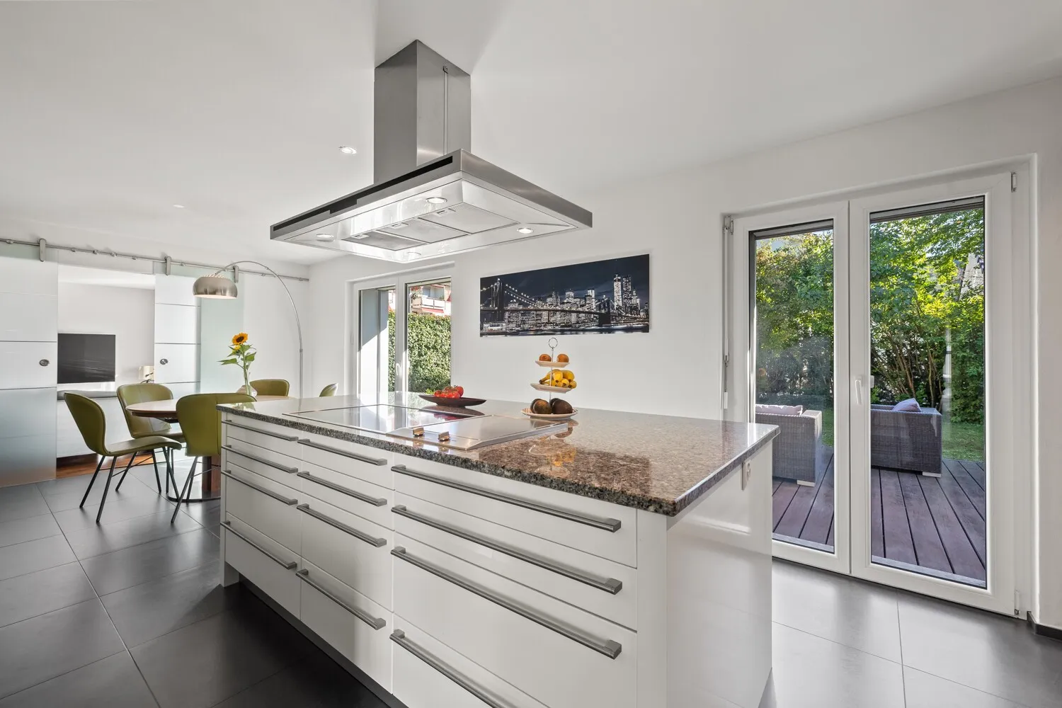 Moderne Einbauküche mit grosser Kochinsel und Zugang zum Sitzplatz