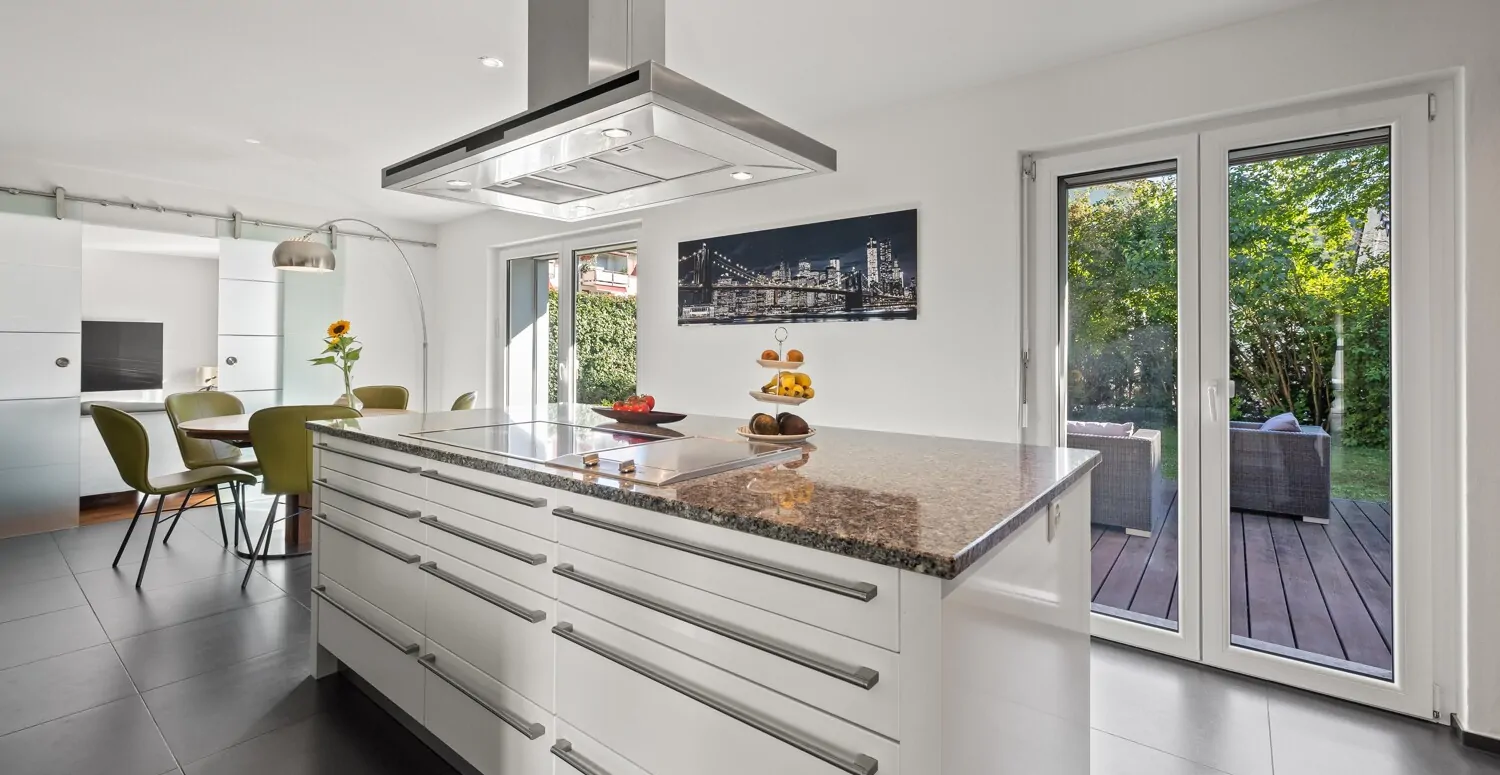 Moderne Einbauküche mit grosser Kochinsel und Zugang zum Sitzplatz