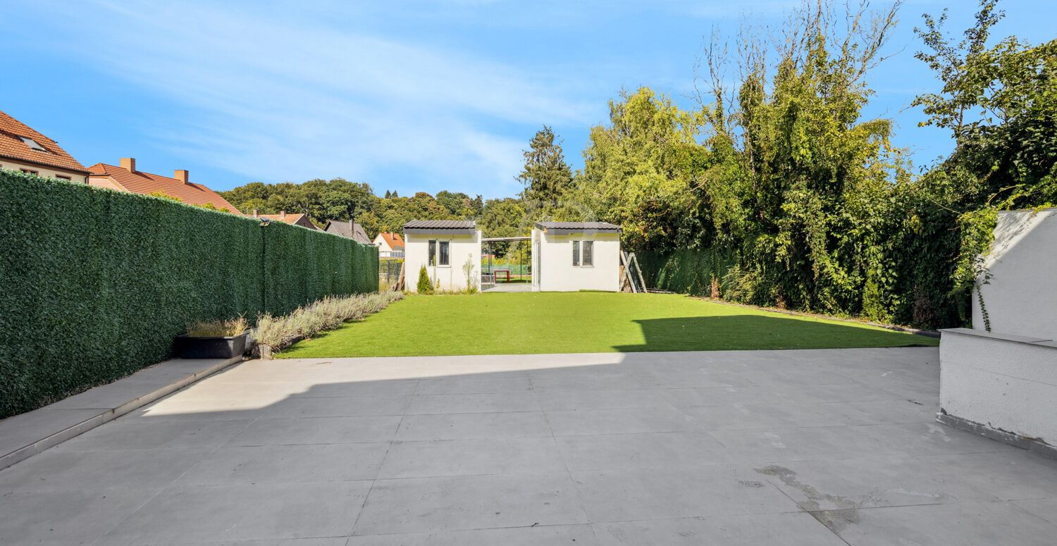 Terrasse mit Blick auf Garten mit Außenküche und Gartenhäuser