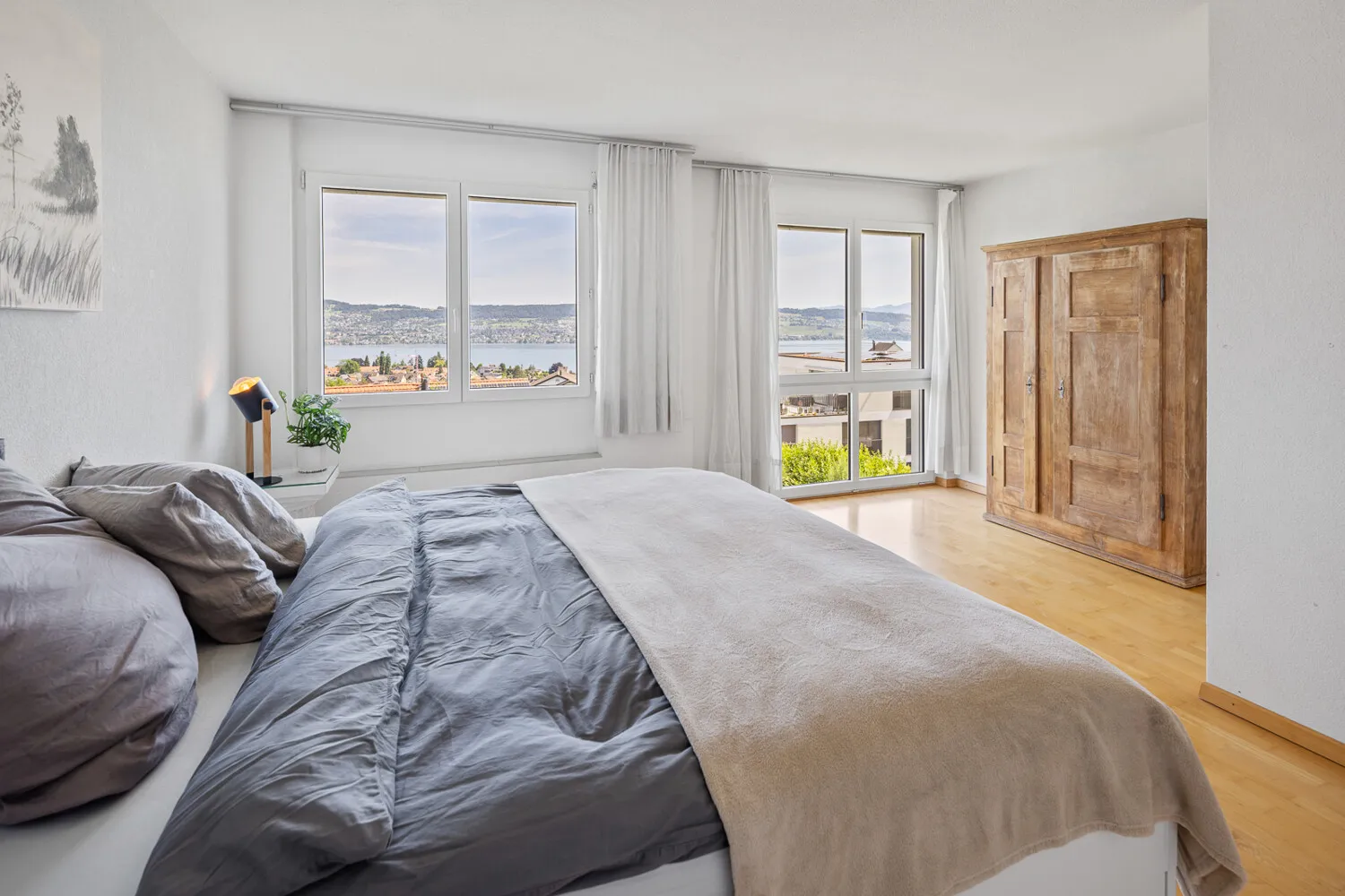 Helles Schlafzimmer mit bodentiefen Fenstern und Blick auf den Zürichsee (EG)