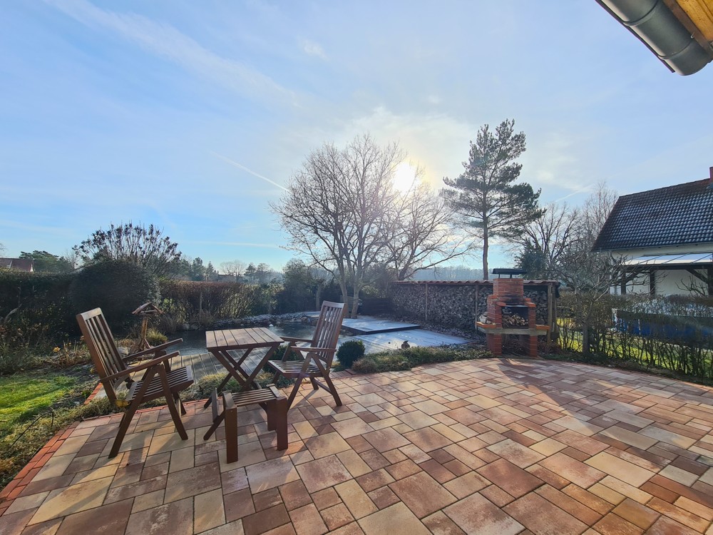 gepflasterte Terrasse mit Steingrill und viel Kaminholz