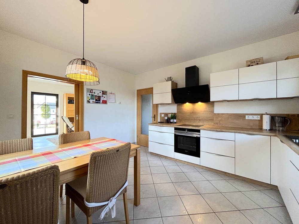 moderne Küche mit hochwertigen Geräten und Schiebetür zum Wohnzimmer