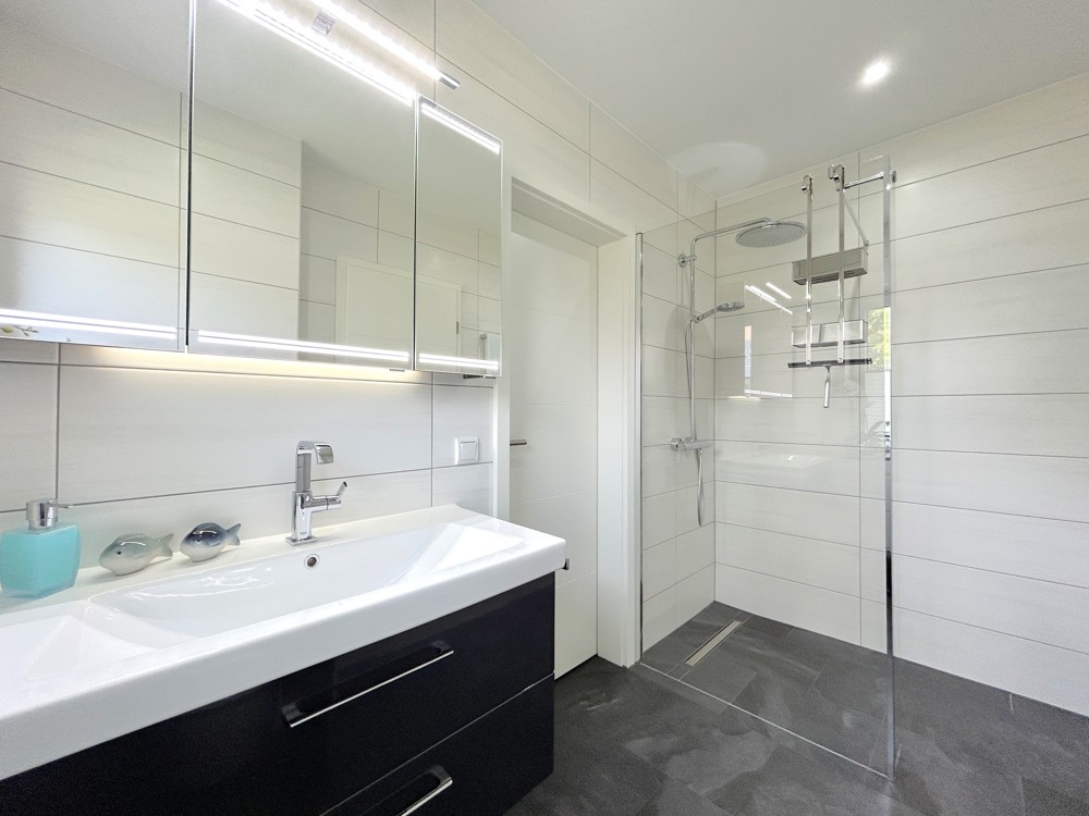 helles Gäste-WC mit ebenerdiger Dusche und angrenzendem Hauswirtschaftsraum