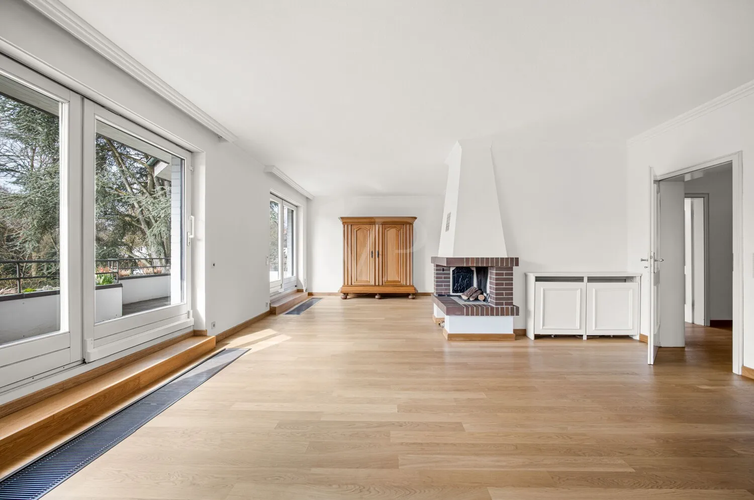 lichtdurchfluteter Wohnbereich mit zentralem Kamin und Zugang zum Balkon