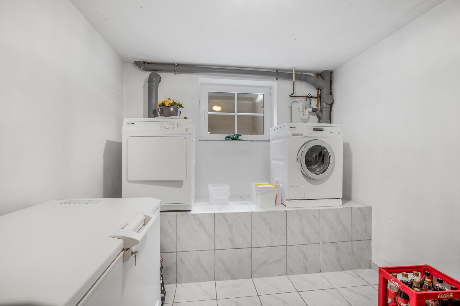 Hauswirtschaftsraum mit erhöhtem Podest für Waschmaschine und Trockner im KG