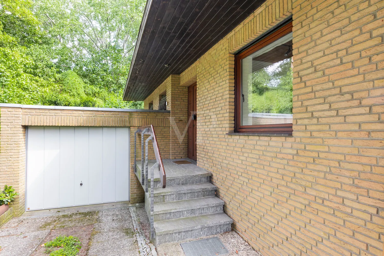 Blick auf den überdachten Hauseingangsbereich und die Garage