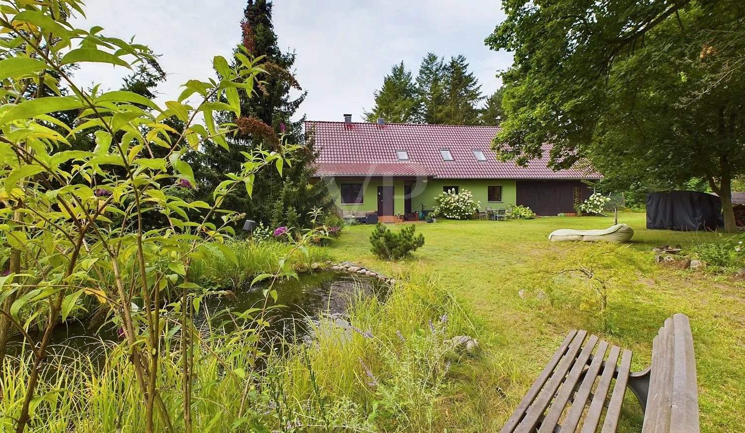 Grundstücksansicht mit Teich und Immobilie