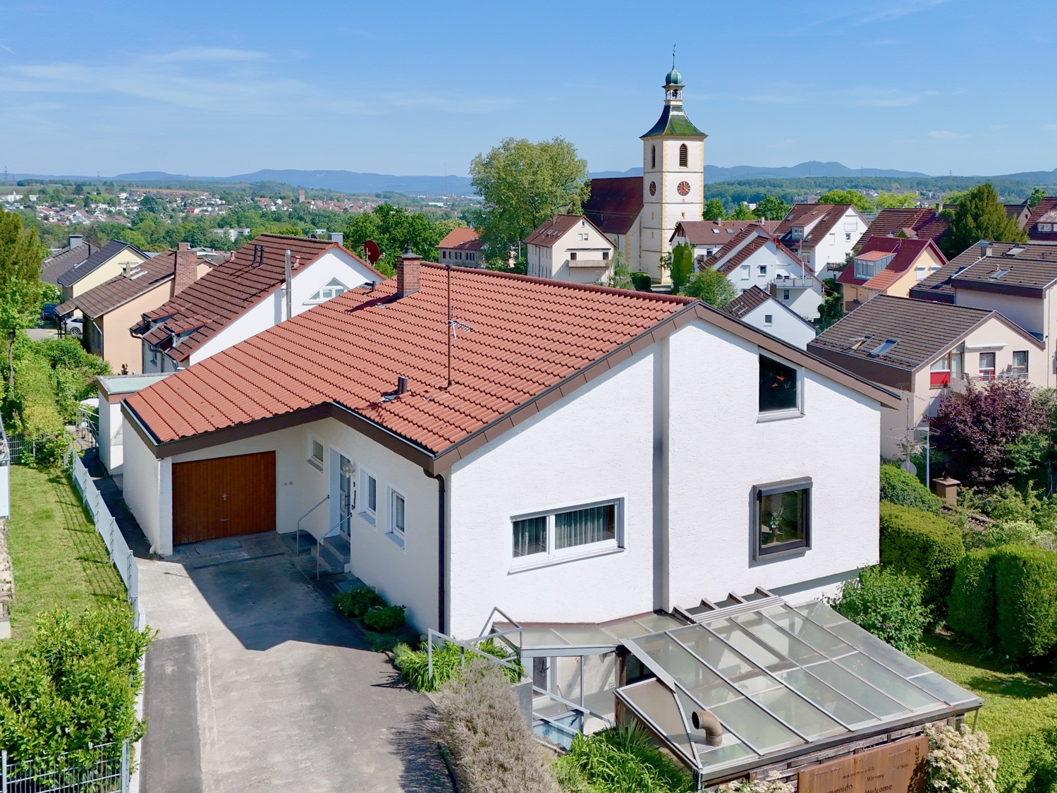 Hausansicht mit Einfahrt, Einzelgarage und überdachter Terrasse der Einliegerwohnung