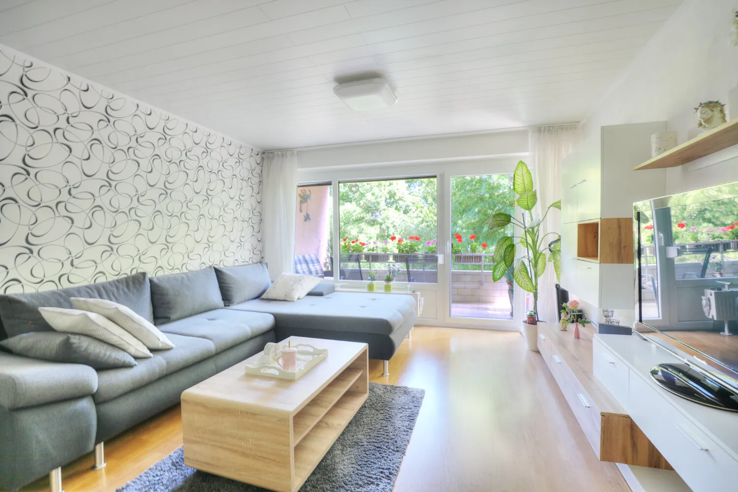 Wohnzimmer mit großer Fensterfront und Zugang zum Balkon